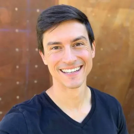 Dan Beall, smiling, in front of a climbing wall